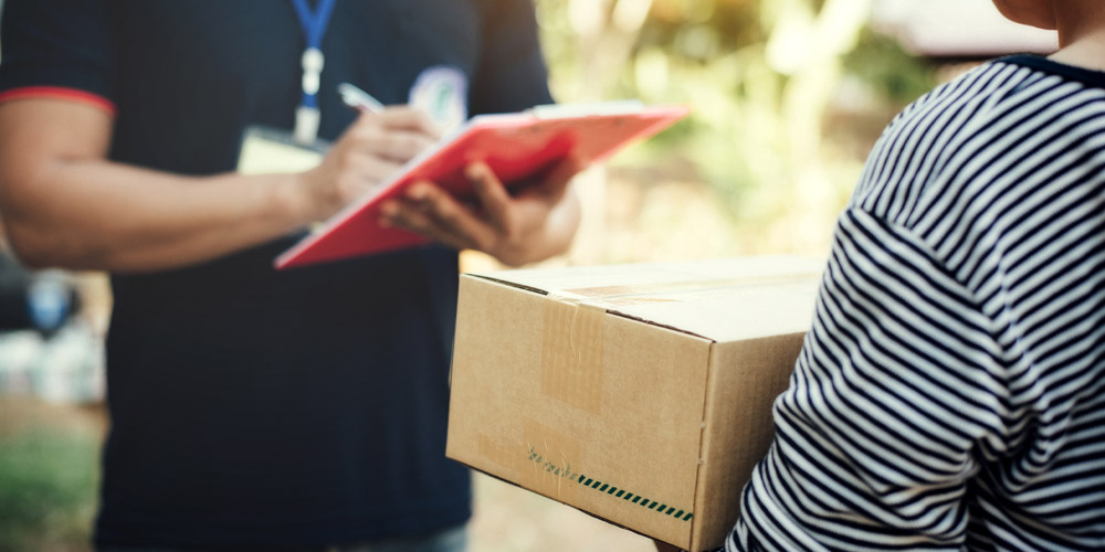 オンラインショッピング利用者が配達員から荷物を受け取っているイメージ画像