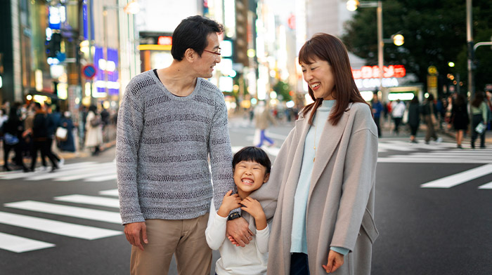 父親、母親、子供がスクランブル交差点の前に並んで立っている画像