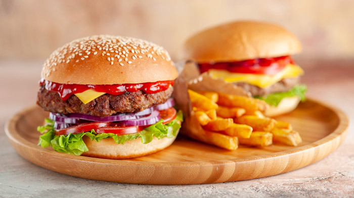 新鮮な野菜とパティをバンズで挟んだハンバーガーがトレーの上に乗ったイメージ画像